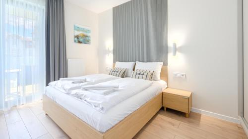 een slaapkamer met een groot bed met witte lakens bij Apartamenty Sun & Snow Euronia in Międzyzdroje