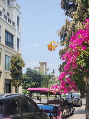 a city street with pink flowers and a bus at Timi Homestay Near the Wave Park Ocean Park 2 in Hòa Bình