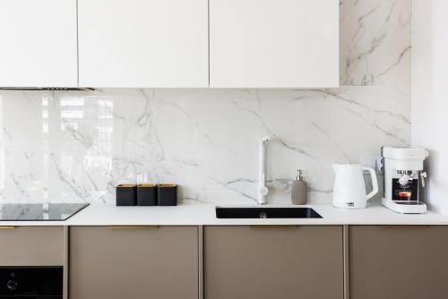 a kitchen with white marble walls and a counter top at Sol Marina Resort Wyspa Sobieszewska II - LoftAffair Collection in Wiślinka