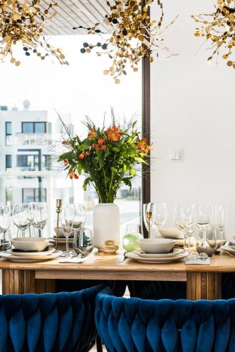 a wooden table with glasses and a vase with flowers at Sol Marina Resort Wyspa Sobieszewska II - LoftAffair Collection in Wiślinka