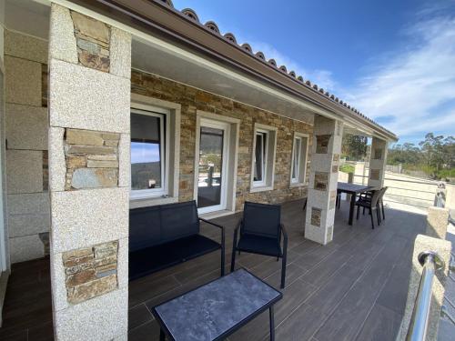 eine Terrasse mit einem Tisch und Stühlen auf einem Haus in der Unterkunft A CASA D'ABAIXO in Cee