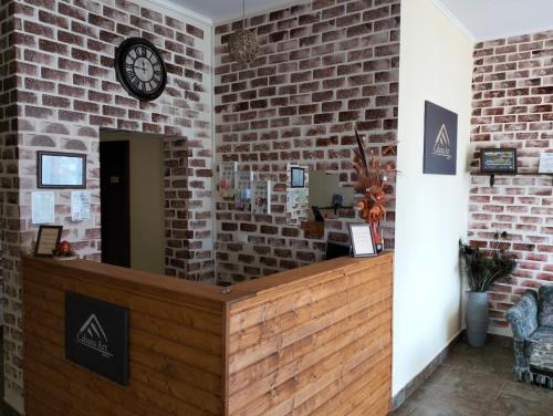 a brick wall with a clock above a reception desk at Pensiunea Cabana Art in Arieşeni
