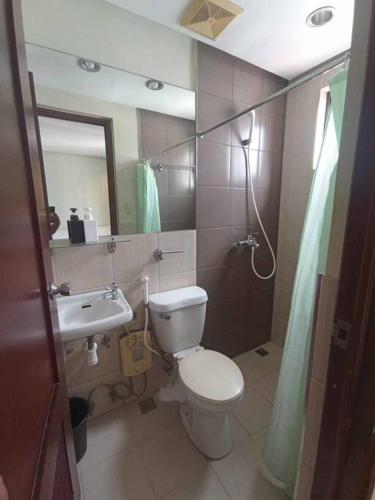 a bathroom with a toilet and a sink and a mirror at Spacious Studio Apartment B503 in Manila