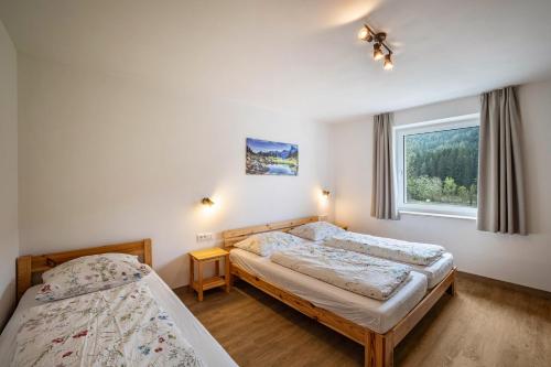 1 dormitorio con 2 camas y ventana en Silbernagl Terrasse - Blick zum See, en Issengo