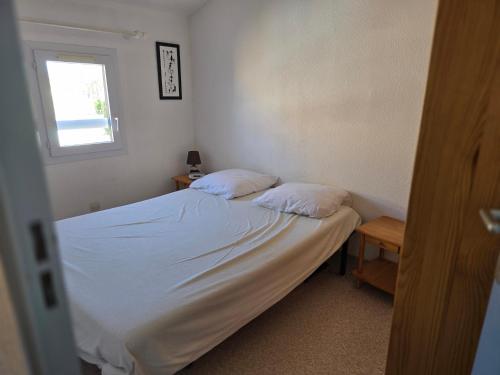 a bed with two pillows in a room with a window at L'échapée Belle - Villa, résidence avec piscine et stationnement à proximité de la mer in Vendres