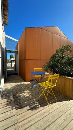 deux chaises jaunes et une table sur une terrasse dans l'établissement L'école de la Guittière, à Saint-Hilaire-de-Talmont