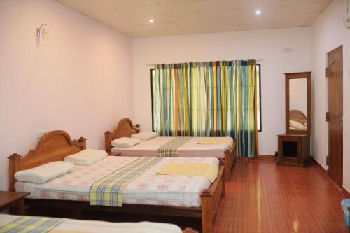 a room with two beds and a window at Royal exotic Wilpathuwa (dilsara ) in Anuradhapura