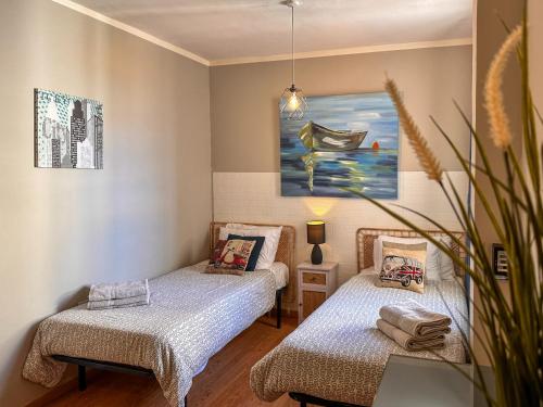 two beds in a room with a painting on the wall at Bayview in St. Julianʼs