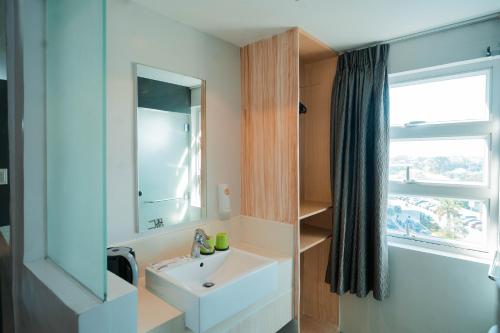 a bathroom with a sink and a mirror and a window at Go Hotels Iligan in Iligan City