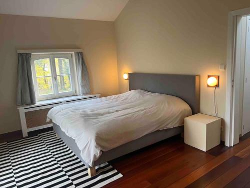 um quarto com uma cama grande e uma janela em Charmante maison dans un coin de verdure à Boitsfort em Bruxelas