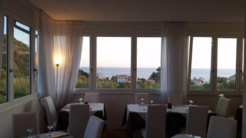 a dining room with tables and chairs and windows at Hotel L'Ogliera in Pomonte