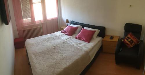 um quarto com uma cama com duas almofadas cor-de-rosa em 2 Bedroom Apartment, Grbavicka em Sarajevo