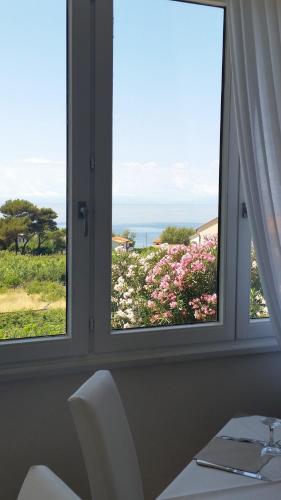 a window with a view of a field of flowers at Hotel L'Ogliera in Pomonte