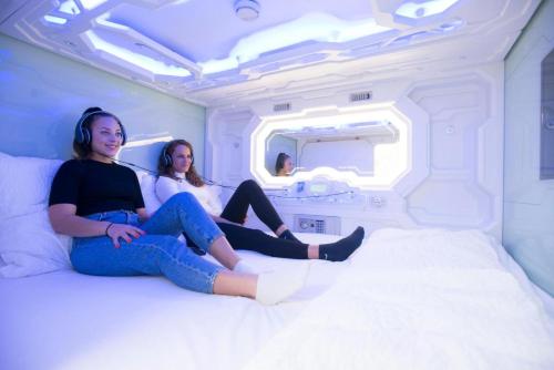 two women sitting on a bed in a white room at Space Home Apartment - Downtown in Vienna