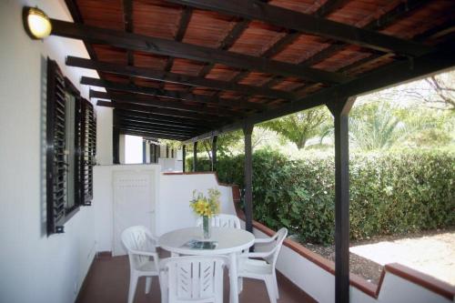 una mesa y sillas en un porche con techo de madera en Villaggio Turistico Grotta dell'Acqua en Peschici