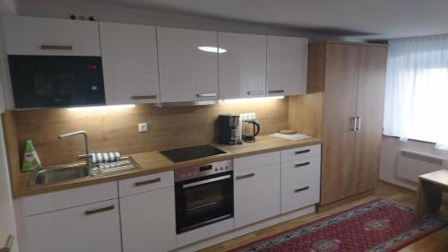 una cocina con armarios blancos y fregadero en Appartement 2 Personen Hallein bei Salzburg en Hallein
