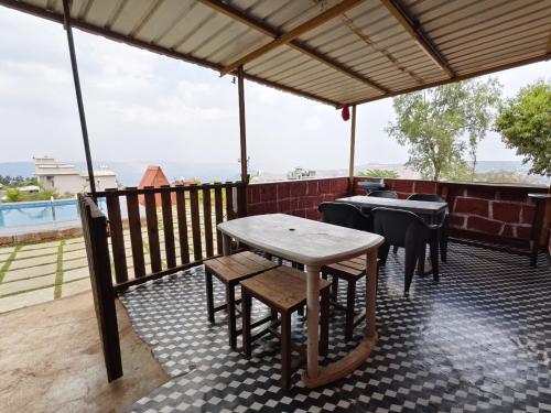 een tafel en stoelen op een patio met uitzicht bij Shayadri Farmhouse in Mahabaleshwar