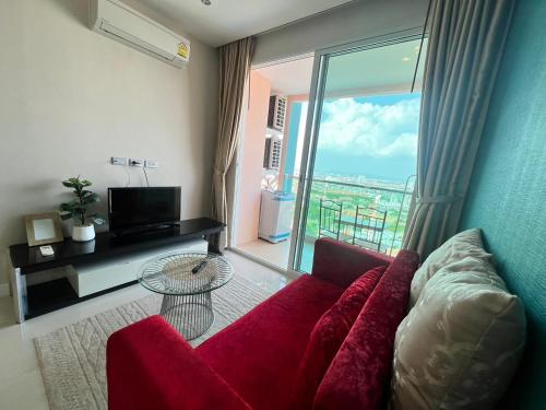 a living room with a red couch and a large window at Grande Cariibbean Pattaya by Thita in Pattaya South
