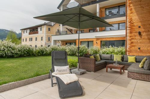 a patio with a chair and an umbrella at AlpenParks Hotel & Apartment Carpe Solem Mariapfarr in Mariapfarr