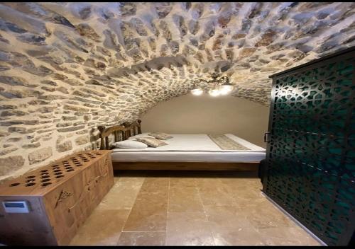 um quarto com uma cama numa parede de pedra em Old City Tourism em Mardin