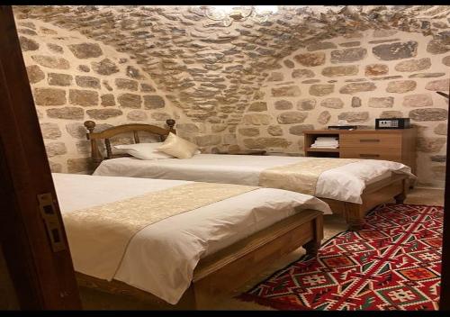 um quarto com 2 camas e uma parede de pedra em Old City Tourism em Mardin