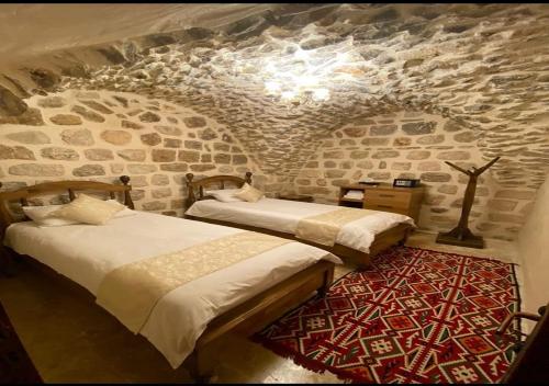 two beds in a room with a stone wall at Old City Tourism in Mardin