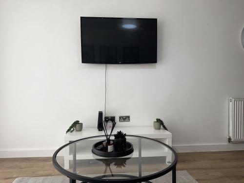 a room with a glass table and a tv on a wall at Deluxe Central Apartment - Smart TV - Fast Wifi - Near Utilitia Arena & ICC in Birmingham