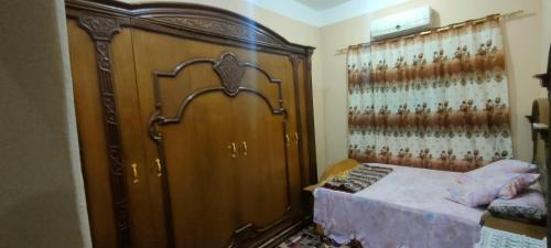 ein Schlafzimmer mit einem großen Bett und einem großen Holzschrank in der Unterkunft أجبن نالعز in Siwa