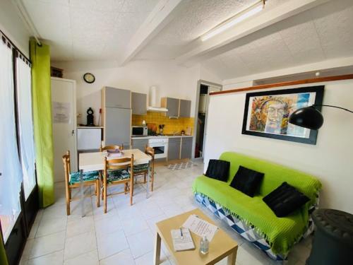 a living room with a green couch and a table at Gîtes de la villa du pin in Ruoms