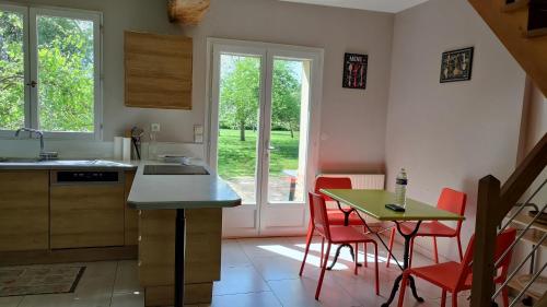 une cuisine avec une table, des chaises rouges, une table et une table dans l'établissement Au coeur des marais, à Varaville