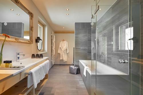a bathroom with a shower and a tub and a sink at HUBER's Boutiquehotel in Mayrhofen