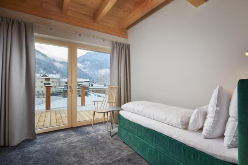 a room with a couch and a balcony with a view at HUBER's Boutiquehotel in Mayrhofen