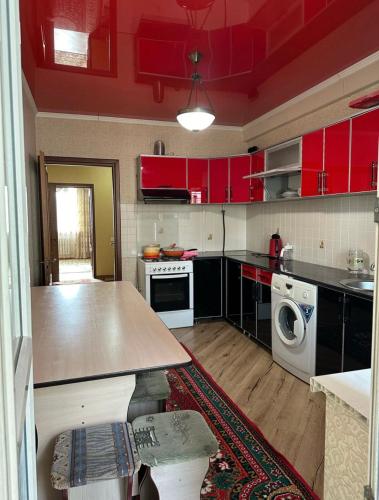 a kitchen with red cabinets and a washer and dryer at guest house djal in Bishkek
