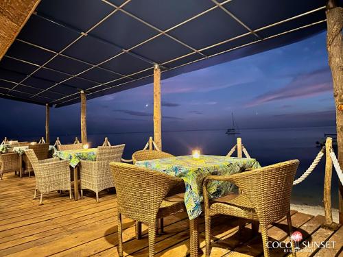 a table and chairs on a deck with a candle at Coco Grove Beach Resort, Siquijor Island in Siquijor