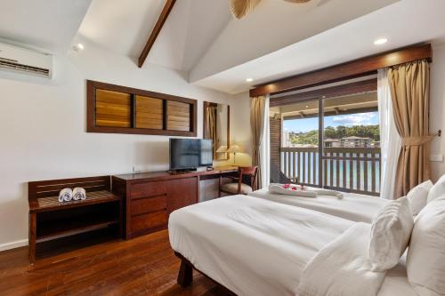 a bedroom with a bed and a television and a balcony at Iririki Island Resort & Spa in Port Vila