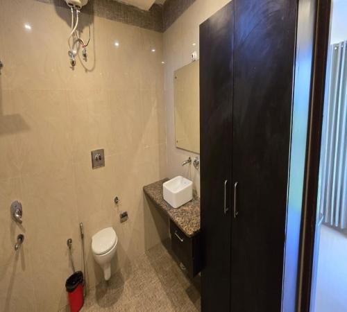 ein Badezimmer mit einem WC, einem Waschbecken und einem Spiegel in der Unterkunft Corbett Courtyard By The Tigers Pugmark in Belparāo