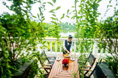 a woman sitting at a table in a garden at Apricot Hotel in Hanoi