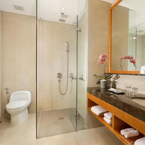 a bathroom with a shower and a toilet and a sink at Resinda Hotel Karawang in Karawang
