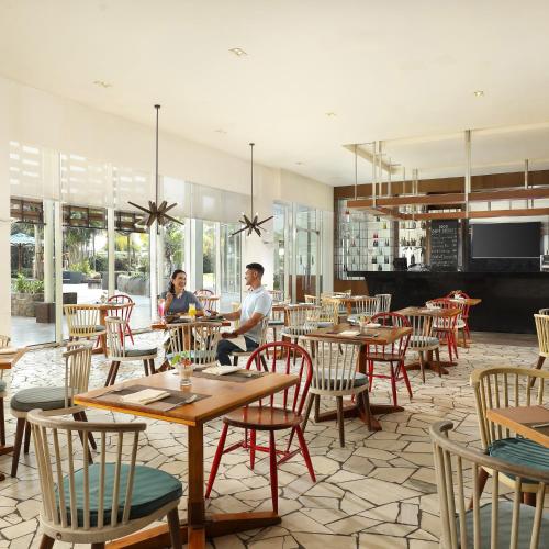 two people sitting at tables in a restaurant at Resinda Hotel Karawang in Karawang