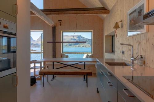 a kitchen with a table and a bench at Minkfarmen, Spacious seaside cabin with scenic view in Ramberg