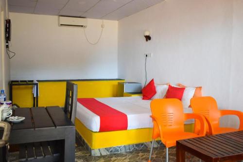 Cette chambre comprend un lit avec des chaises orange et une table. dans l'établissement Golden Beach Cottages, à Trincomalee