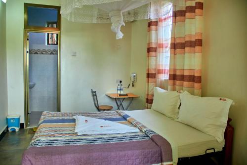 Schlafzimmer mit einem Bett, einem Fenster und einem Tisch in der Unterkunft La Vista Garden Hotel in Turiani