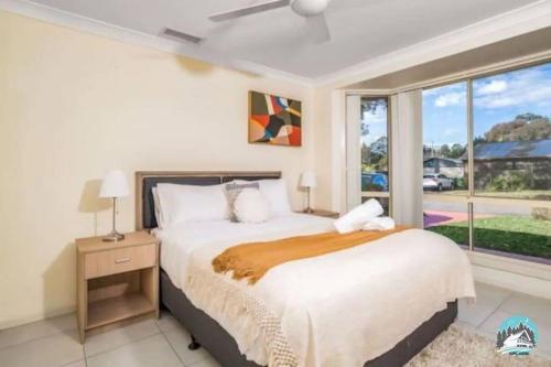 a bedroom with a bed and a large window at Aircabin - Tuggerawong - Lake Front - 9 Beds House in Karraganbah
