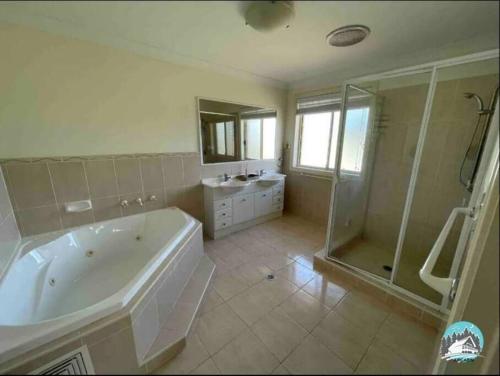 y baño grande con bañera y ducha. en Aircabin - Tuggerawong - Lake Front - 9 Beds House, en Karraganbah
