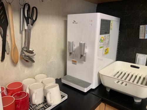 Una encimera de cocina con tazas y un refrigerador blanco. en Cocoa Guesthouse, en Seúl