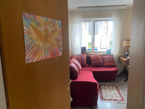 ein Wohnzimmer mit einer roten Couch und einem Gemälde an der Tür in der Unterkunft Nördlingen im Ries - Königsbergerstr. - kleines Gästezimmerchen in Nördlingen