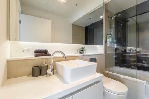 ein Badezimmer mit einem Waschbecken, einem WC und einem Spiegel in der Unterkunft Spacious 2 bedroom apartment with Free parking-00189 in Melbourne