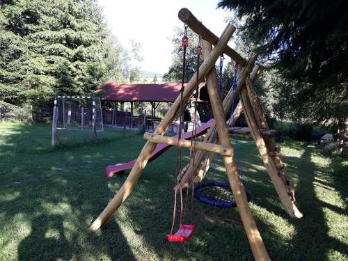 einen Spielplatz mit einer Schaukel im Gras in der Unterkunft Any Kulcsosház in Sicasău