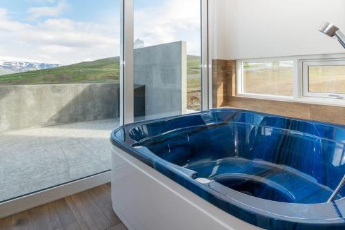 uma casa de banho com uma banheira azul em frente a uma janela em Private cottage, elegance & amazing view em Akureyri