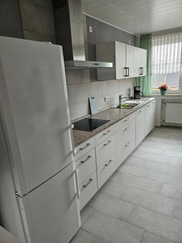 eine Küche mit weißen Schränken und einem weißen Kühlschrank in der Unterkunft Ferienwohnung  Monteurwohnung - b63890 in Bremerhaven